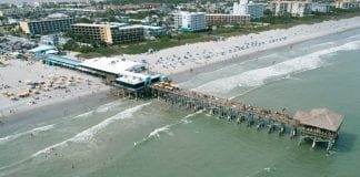 drone-video:-surfers,-beachgoers-at-cocoa-beach-pier,-great-place-to-watch-rocket-launch